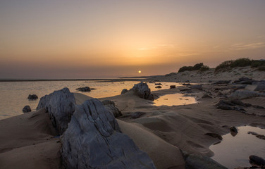 landscape of a beach with rocks at sunset