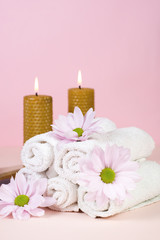 Fototapeta na wymiar Set of towels with flowers for Spa treatments on a pink background. Copy space