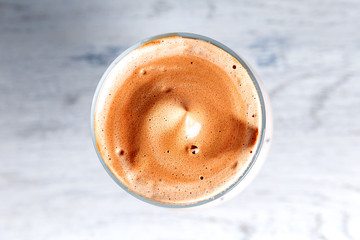 Iced korean Dalgona Coffee, a trendy fluffy creamy whipped coffee with ice. top view, white wooden background