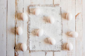 Fototapeta na wymiar White chicken eggs lying on a white painted wooden surface. Background for livestock products.