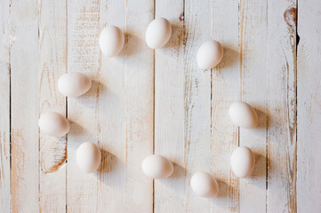 White chicken eggs lying on a white painted wooden surface. Background for livestock products.