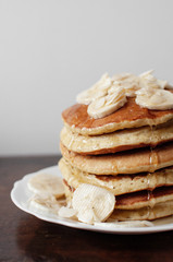 Stack of pancakes on a plate with banana and almonds