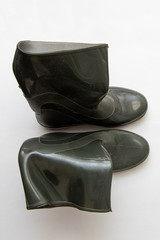 Dark crumpled rubber boots stand, isolated forn, close-up