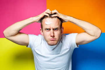 Portrait of a young, handsome, cheerful guy on a multi-colored background, dressed in a white...