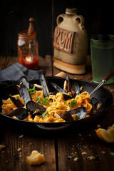 Pasta with mussels and sauce in a frying pan