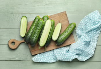 Board with green cucumbers on wooden background