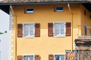 Italian windows on the yellow wall facade with open brown color classic shutters