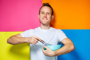 young guy man in a white T-shirt, colorful background, kitchen utensils, cook, emotions photo