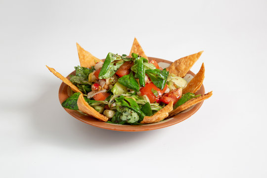 Horizontal image of oriental food Fattoush dish with tortilla chips, crackers and vegetable salad on white background. 