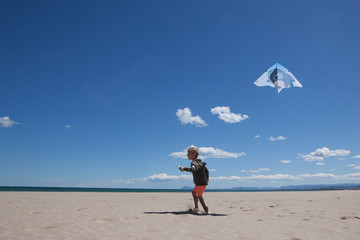 Happy boy running on the beach in summer with a kite. Beautiful sea and sand