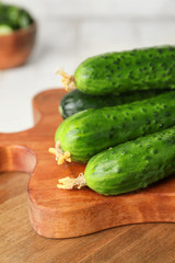 Board with green cucumbers on table