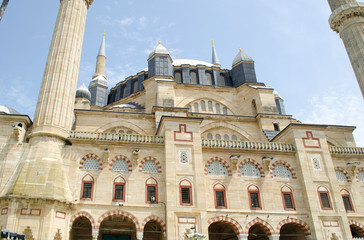 Sunny, clear blue sky. Minarets of light yellow limestone, marble, dark blue, gray domes on roof of mosque. Bright juicy fresh green leaves on trees. Copy space. Selective focus Turkey, Edirne