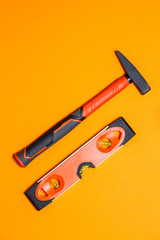 Tools for repair. Hammer for nails and level on an orange background. Toolkit for the wizard