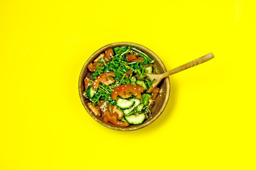 Veggie vegetable salad in a wooden bowl on a yellow background, top view, flat lay