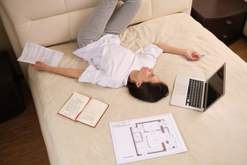 Young  woman businessman on self-isolation during a coronovirus pandemic COVID-19 on self-isolation works at home, lying on bed, checks mail, does his work remotely, telework