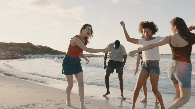 Diverse group of friends dancing along the seashore. Group of men and women enjoying a summer weekend on a beach.
