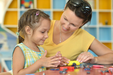 Portrait of little girl and mother playing at home