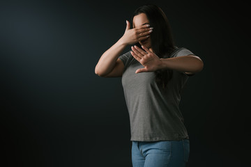 Plus size girl expressing blindness and denial with stop gesture isolated on black