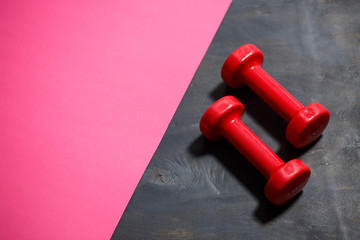 Red dumbbells for sports on a pink background. Healthy lifestyle. Fitness equipment for weight training. Muscle development and fitness training