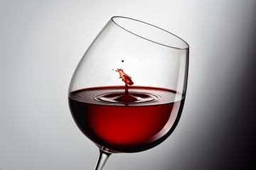 A glass of red wine. Splash with drops close-up isolated on black-white background.