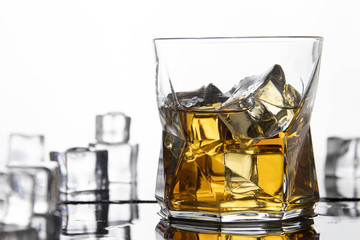 Glass of whiskey with ice. Alcoholic bewerahe with reflection and white background