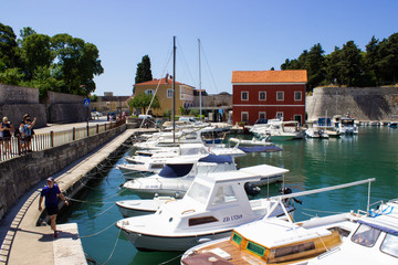 Fototapeta na wymiar Zadar, Croatia; 07/17/2019: Lucica Fosa (Zadar harbour) full of boats and walls of the city in the old town of Zadar