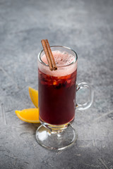 Mulled wine in a glass, tall, transparent glass with cinnamon and lemon