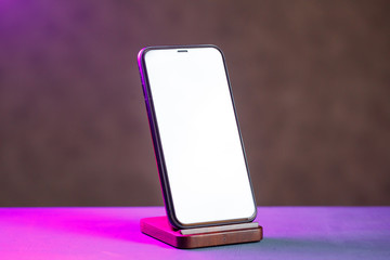 A black phone stands on a wooden stand. Wireless Charging for Phone © DSMT