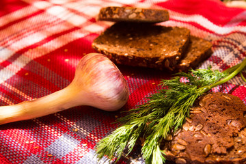 Gray bread on a tablecloth with dill, garlic, wooden table