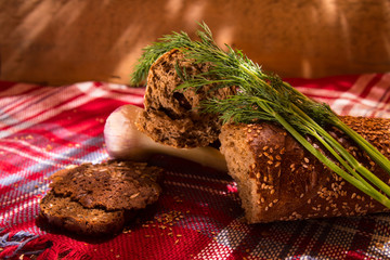 Gray bread on a tablecloth with dill, garlic, wooden table