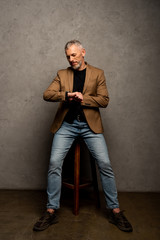 bearded businessman looking at watch and sitting on grey