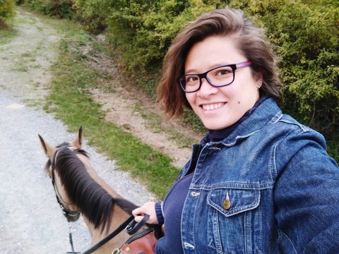 Portrait Of Smiling Young Woman Riding Horse On Road