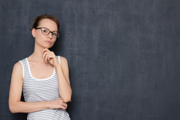 Portrait of focused girl with glasses, touching chin with hand