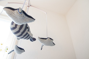 Love at home: Lovely knit baby crib mobile with white wall in low angle view