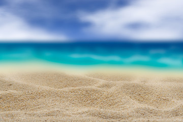 Fototapeta na wymiar Background. Clean sand on a background of the blurry turquoise sea. Cloudy sky.