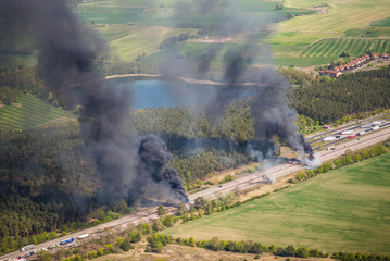 Fire on highway  - strong black smoke rises to the sky, flames are visible - two trucks caught fire on a highway and burn out completely - aerial view 