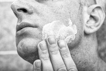 Young caucasian handsome man put moisturizer, cream face or sunscreen on hand for nourishing his body and face skin, protecting from sunlight. Cool guy has beauty skin, he look after himself well.