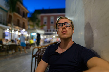 Young handsome tourist man with eyeglasses thinking outdoors