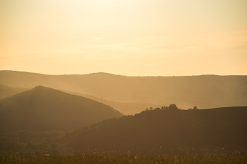 summer fiery red sunset in the mountains against the background of trees