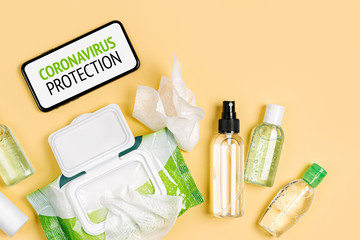 Smartphone with disinfectant spray,   antibacterial wet wipes and hand sanitizer on yellow background. Personal hygiene product for protection virus, flu, coronavirus, COVID-19