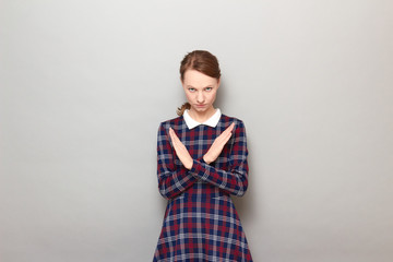 Portrait of serious girl making cross with hands, showing stop gesture