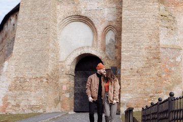 young happy couple on old city background. A love couple enjoying a walk in the courtyard of the old city. Against the background, red brick walls. selective focus
