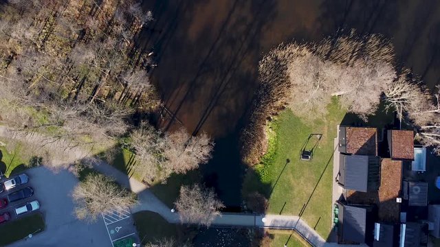Top-down aerial drone view of N&auml;&auml;s Fabriker, Tollered, Sweden. Camera moves away from shore towards brown and muddy waters.