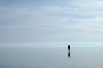 Lonely, thoughtful  man in the middle of sea watching horizon at sunset