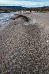 Cracked red clay and white salt on the surface in a dried riverbed in the desert of New Mexico, USA
