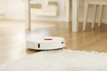 Robot vacuum cleaner performs automatic cleaning of the apartment at a certain time. white robot...