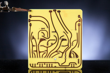 Close up of raw print circuit board pcb supported by third hand. Black background