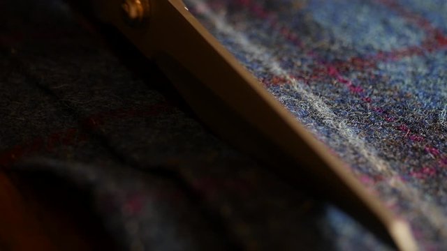 close up 4k professional shot of Scissors cutting tweed wool fabric : bespoke suit fabric close-up, This male Dressmaker is cutting pattern in cloth for made to mesure bespoke suit.