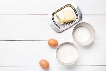 Ingredients for Breakfast and baking: eggs, flour, sugar and butter on a black background.