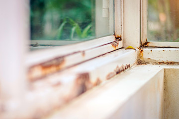 Close up of rust on an old white iron window in the corner of the frame with a blurred background